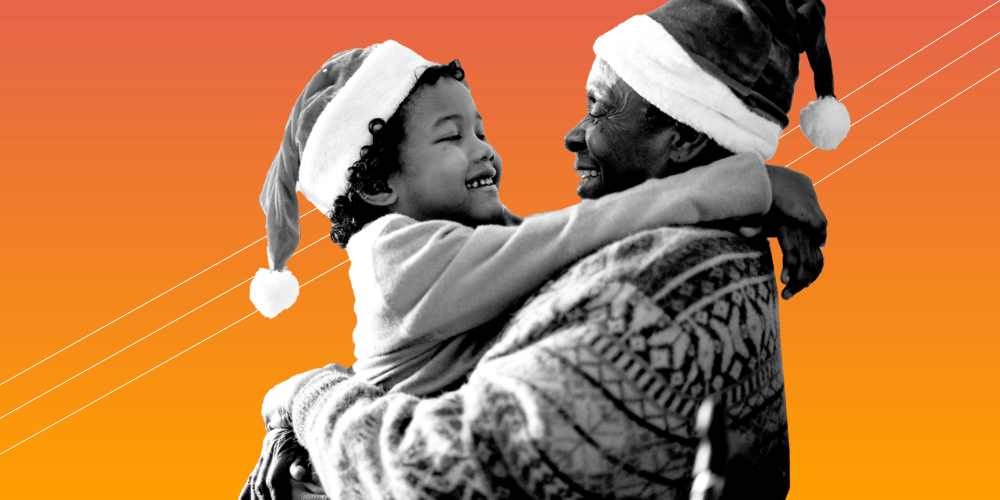 A man wearing a Santa hat who is lifting up a child wearing a Santa hat.