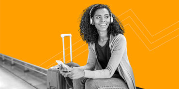 young woman wearing headphones sitting next to luggage sharing 21 little-known ways that travel pros globetrot for cheap