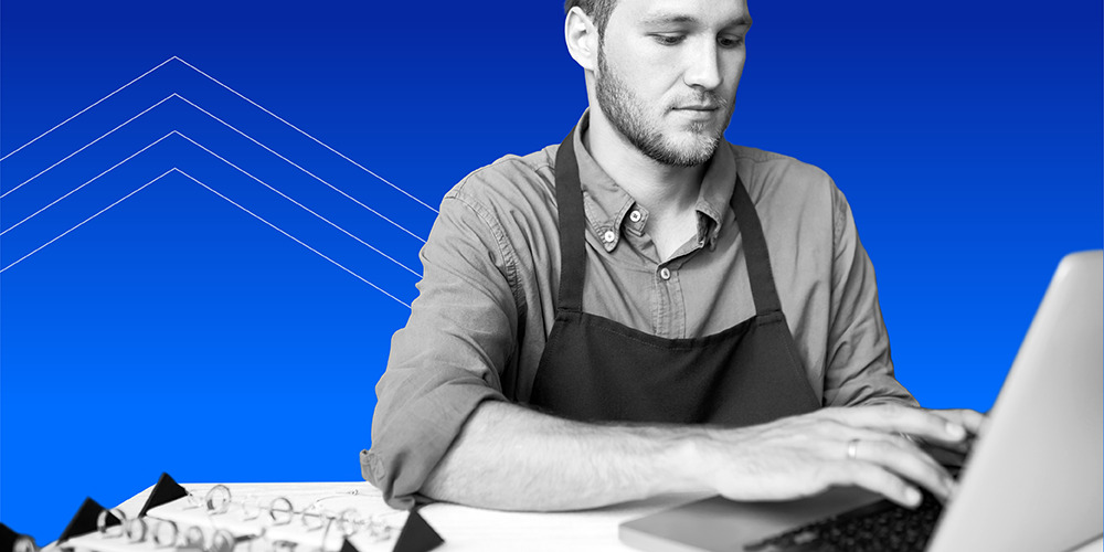 young man working on laptop and using a savings worksheet to crush money goals