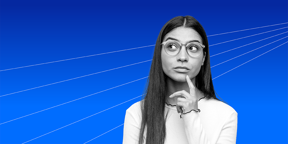 woman with long hair and glasses holding her finger to her chin in a pensive pose