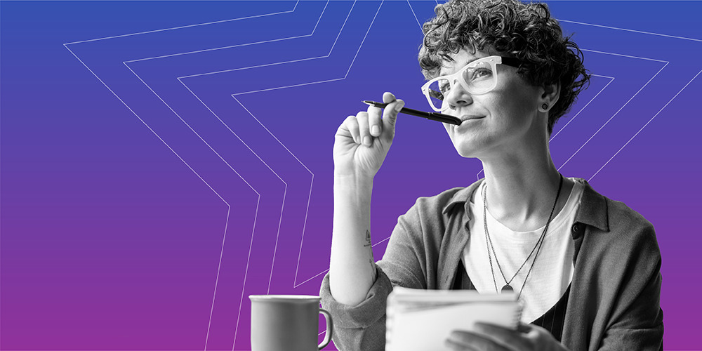 young woman with curly hair and glasses chewing on her pen while learning 3 steps to build female financial confidence