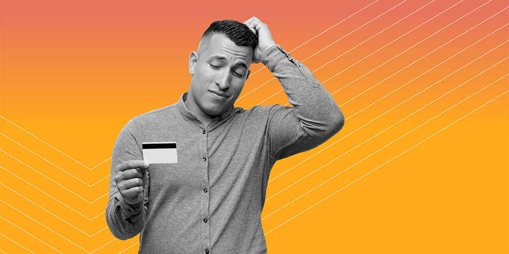 man scratching his head and holding a credit card wondering how bad is it to miss a credit card payment?