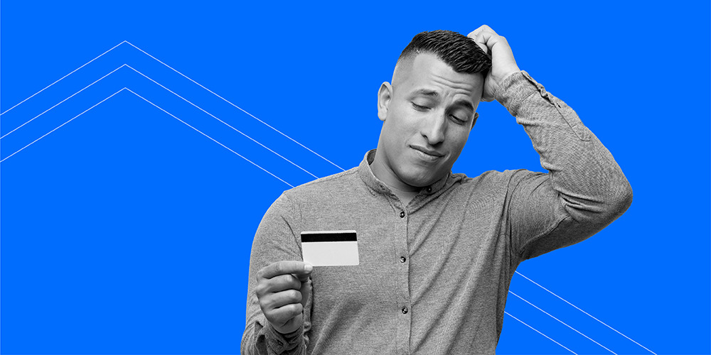 man holding credit card and scratching his head after learning 5 ways you get tricked into toxic spending