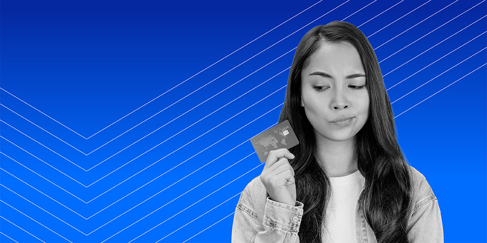 woman with long dark hair in a denim shirt holding a credit card