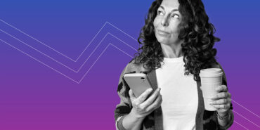 woman with curly hair holding her phone and coffee learning about 5 expenses to trim instead of coffee