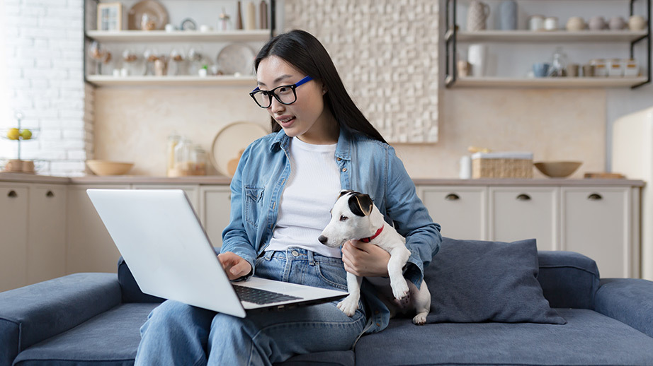 woman with her dog on couch using a laptop