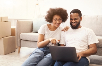 young couple in white t-shirts working on the computer in front of couch