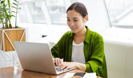 woman in green shirt working on laptop
